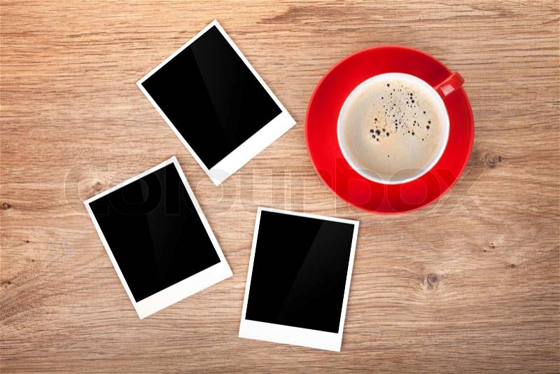 Cup of coffee and three photo frames on wooden table, stock photo