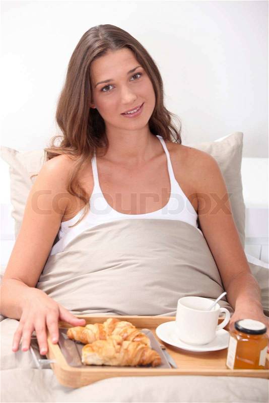 Woman eating breakfast in bed, stock photo