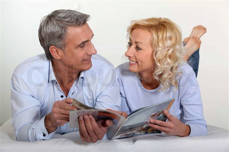 Married couple reading magazine, stock photo