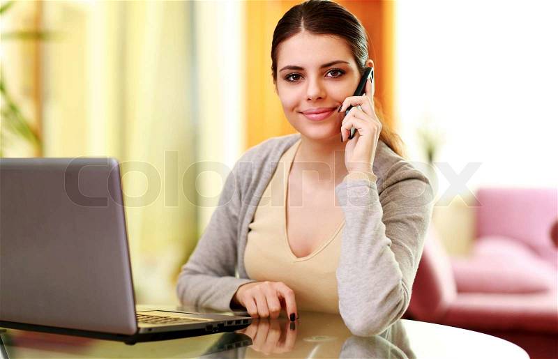 Young happy smiling woman talking on the phone at home, stock photo