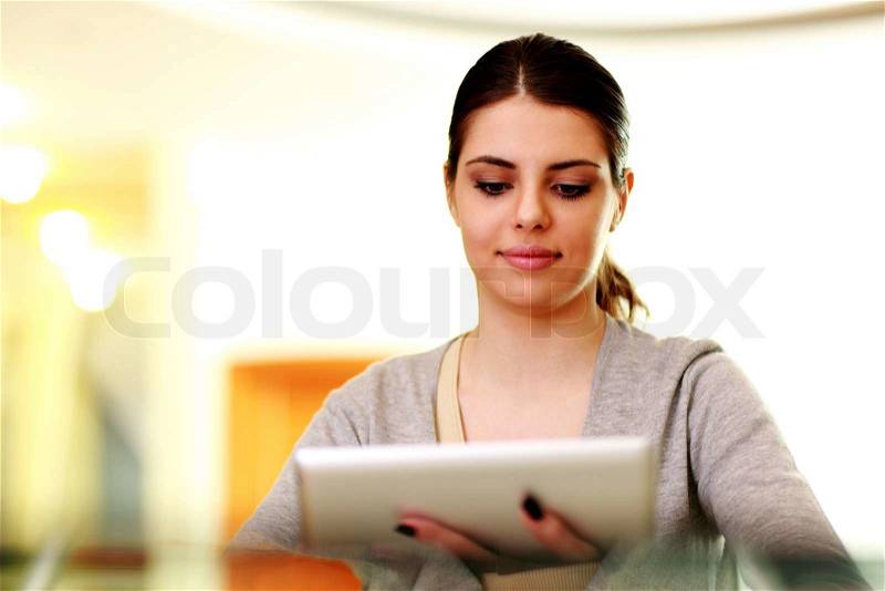 Young happy woman holding tablet computer at home, stock photo