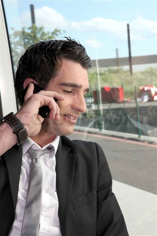 Man in suite on telephone riding tram, stock photo