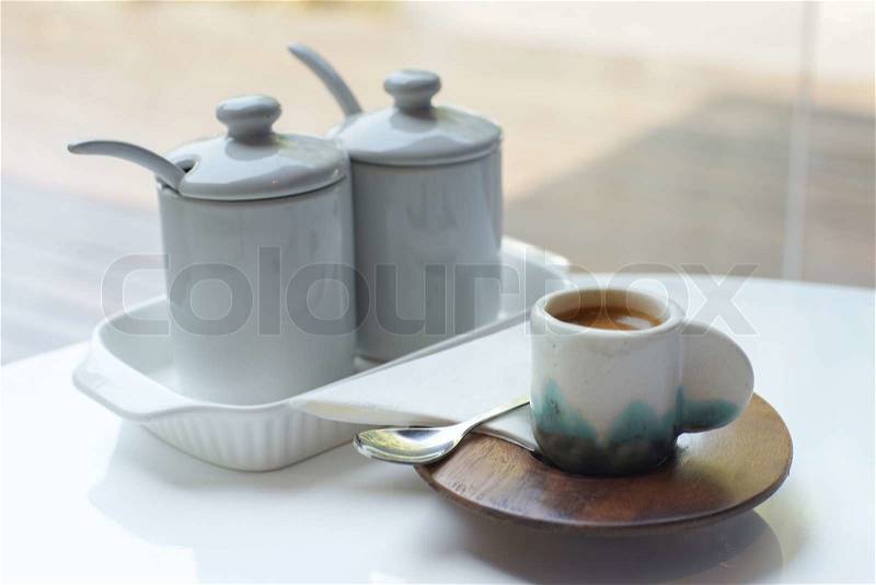 Small cup of coffee on white table with set of sugar pots, stock photo