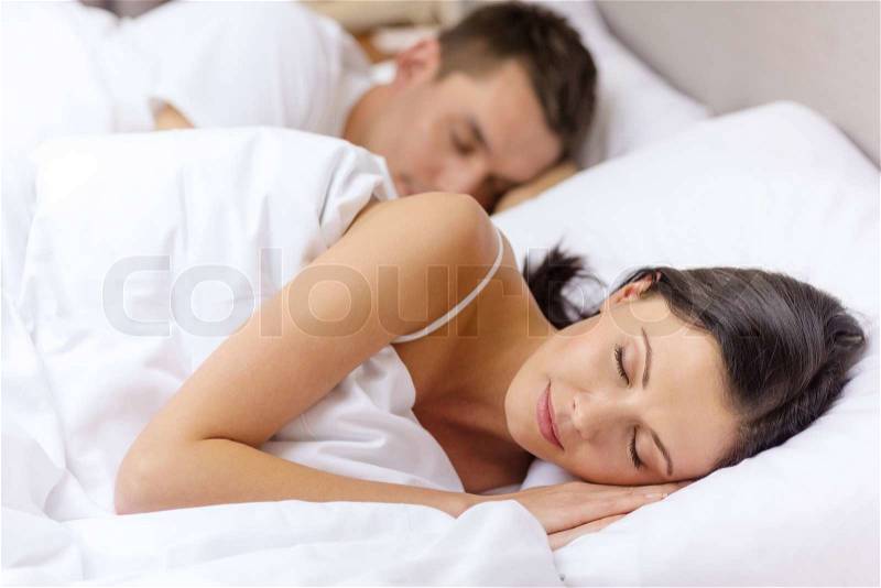 Hotel, travel, relationships, and happiness concept - happy couple sleeping in bed, stock photo