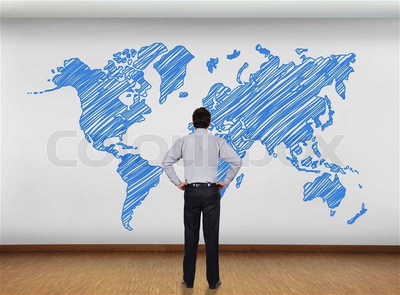 Businessman in office looking at wall with world map, stock photo