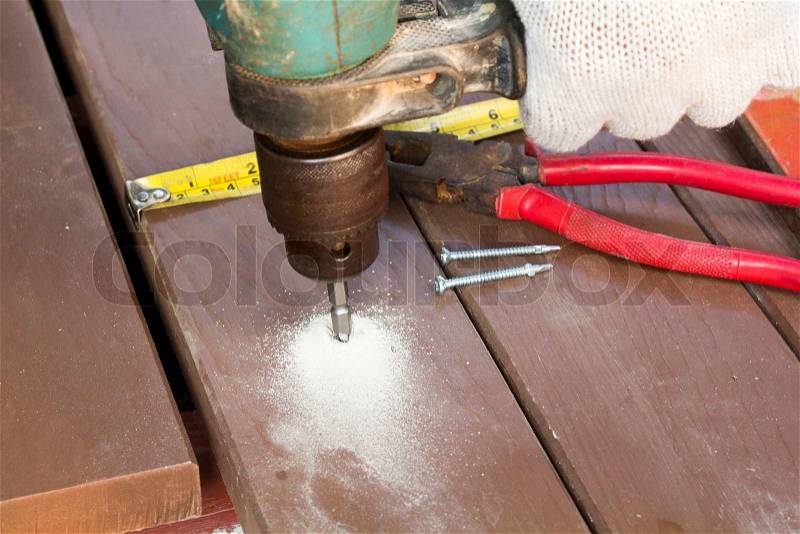 Drill setting screws in artificial wood for patio, stock photo
