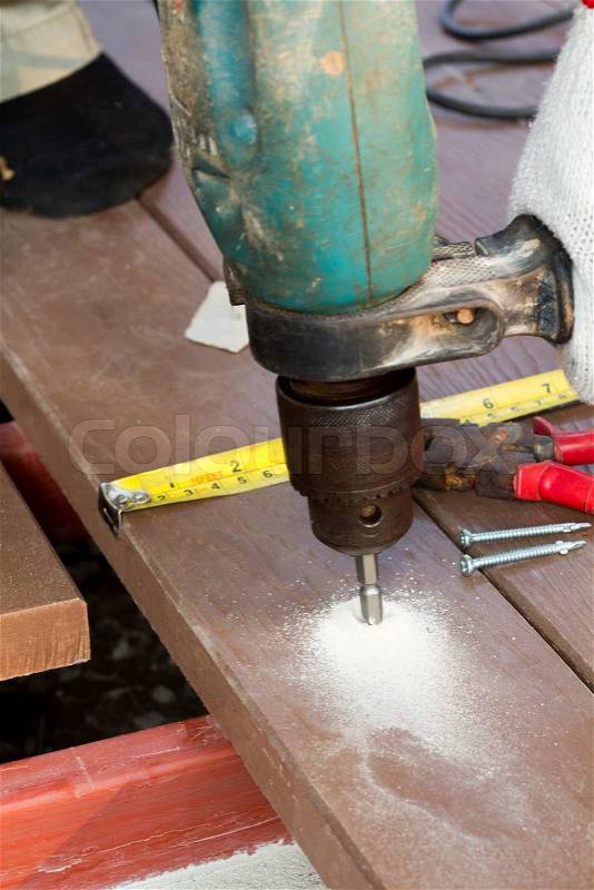 Drill setting screws in artificial wood on metal beams for patio, stock photo