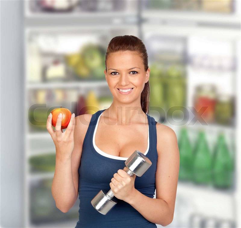 Attractive girl eating a apple of de fridge after training, stock photo