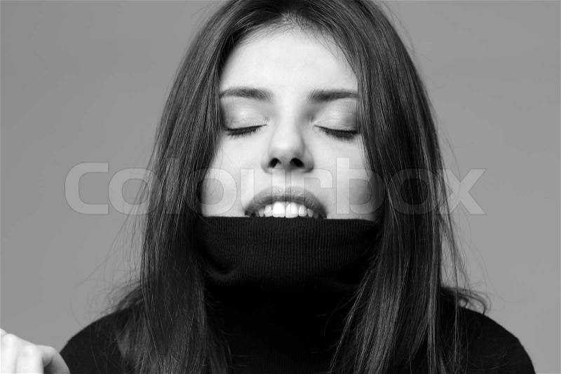 Black and white portrait of a young woman bites her sweater, stock photo