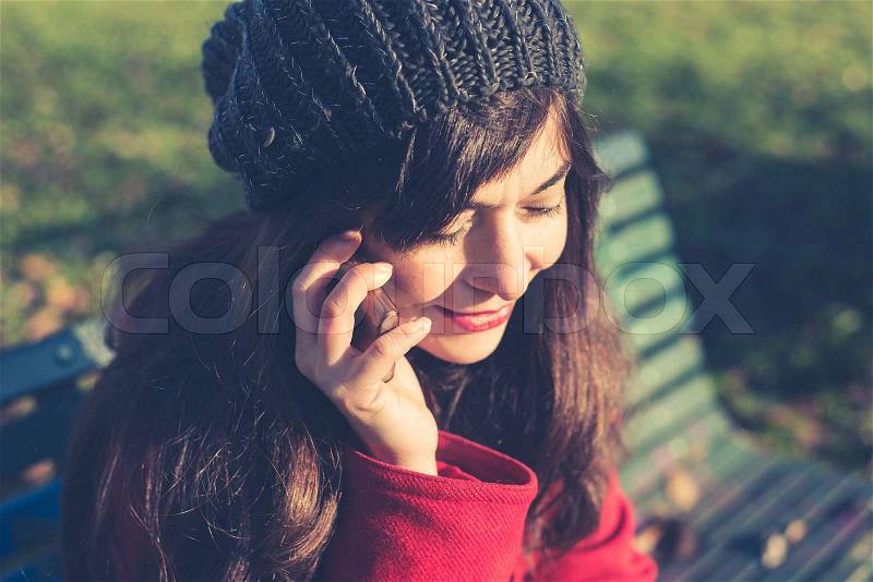 Beautiful woman red coat winter bench park cellphone, stock photo