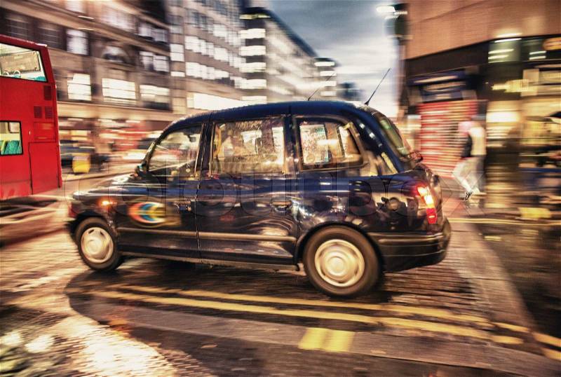 Motion blur picture of Black Cab at major road intersection in London night - UK, stock photo