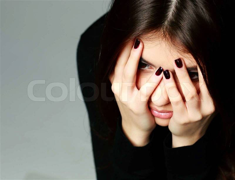 Closeup portrait of a woman with hands over her head on gray background, stock photo