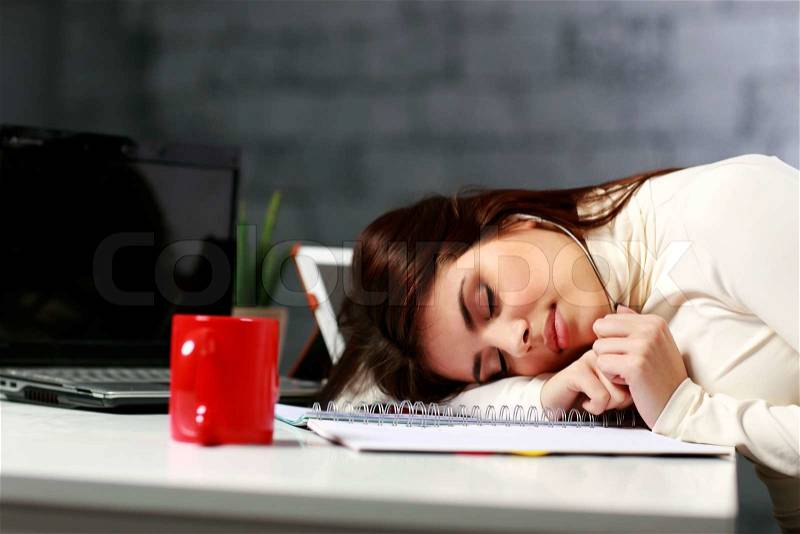 Young tired student fallen asleep at the table, stock photo