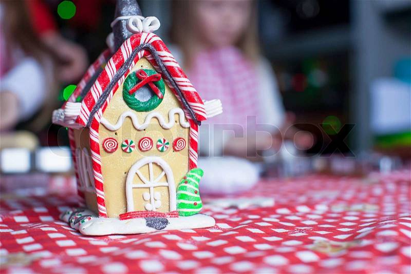 Gingerbread fairy house decorated by colorful candies on a background of little girl, stock photo
