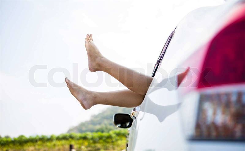Woman legs out the windows in car above the clouds (Summer road trip car vacation concept), stock photo