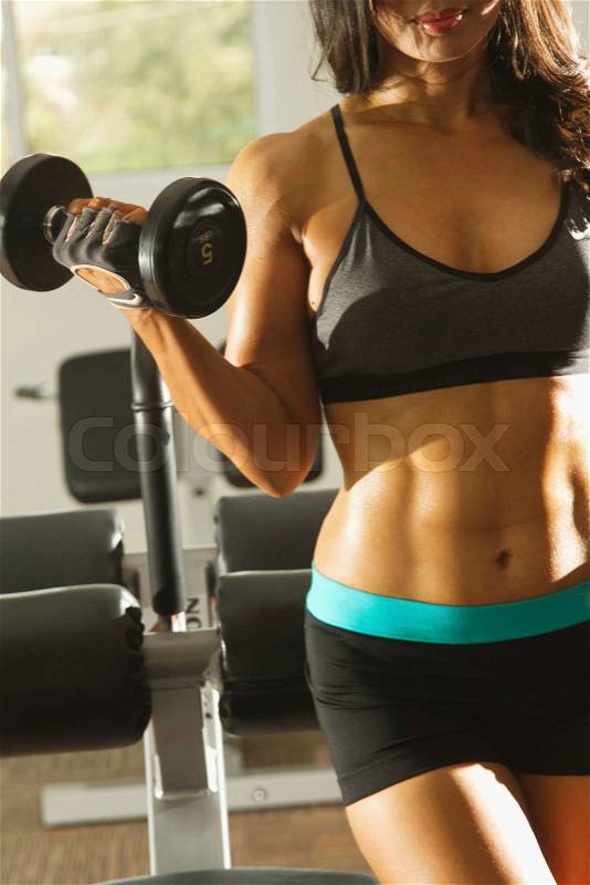 Torso of a young fit woman lifting dumbbells, stock photo