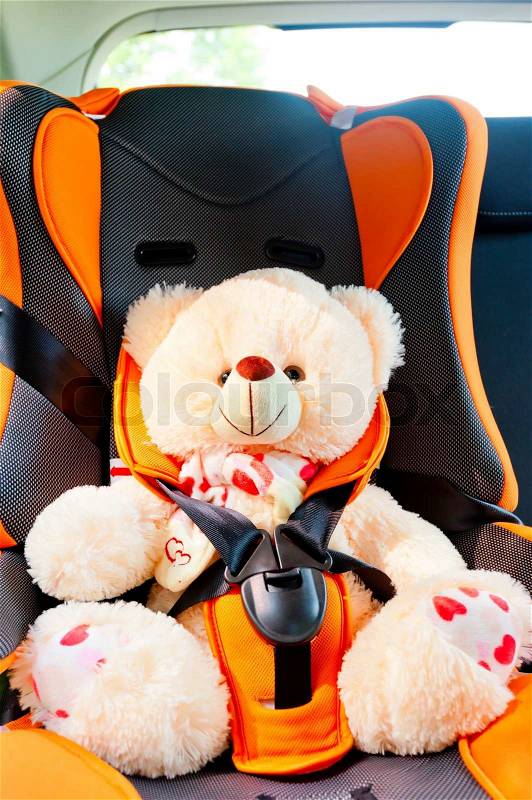 Bear strapped in a child seat in the car, stock photo