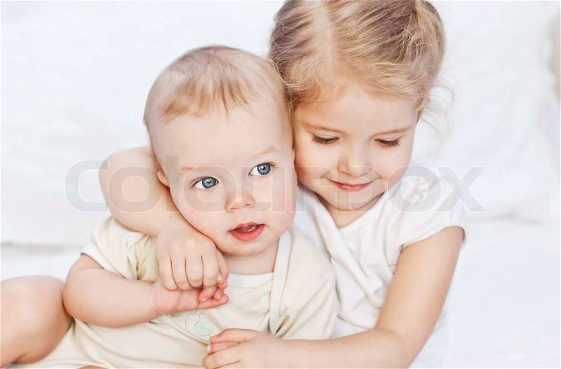 Happy little sister hugging her brother on a white background, stock photo