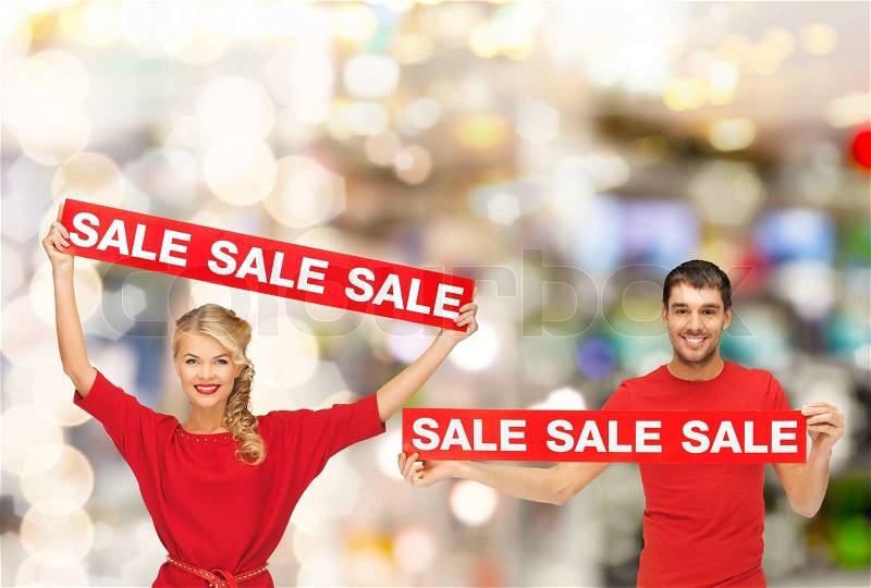 Shopping, sale, mall and christmas concept - smiling woman and man with red sale signs at shopping mall, stock photo