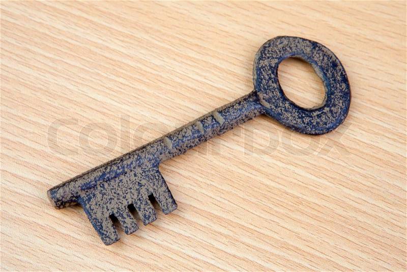 Photo of old bronze key on wooden surface, stock photo