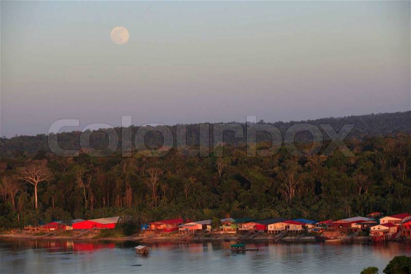 Amazon Landscap with a village under the moon in the light of the evenig in front of a riveri, stock photo