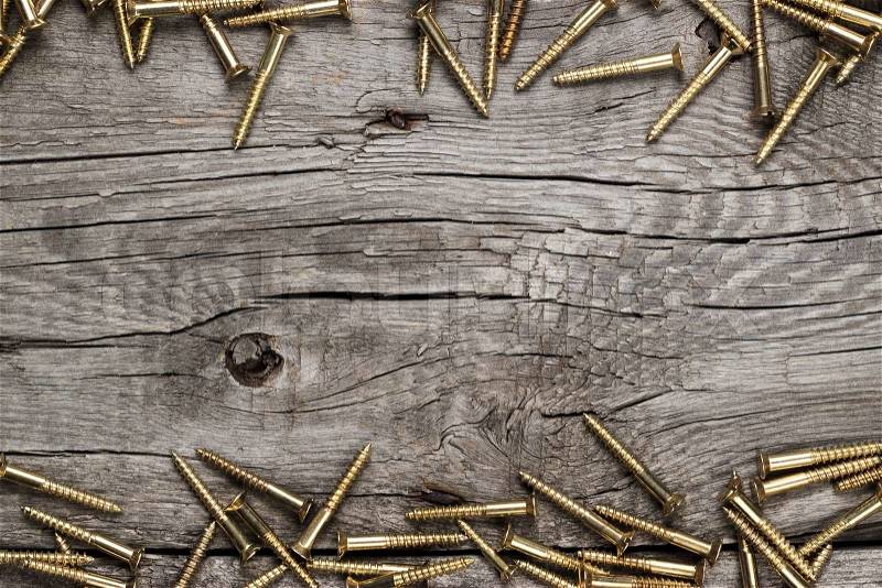New yellow screws on the wooden table background, stock photo