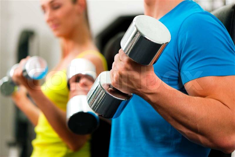 Couple in the gym, rivaling each other, exercising with dumbbells , stock photo