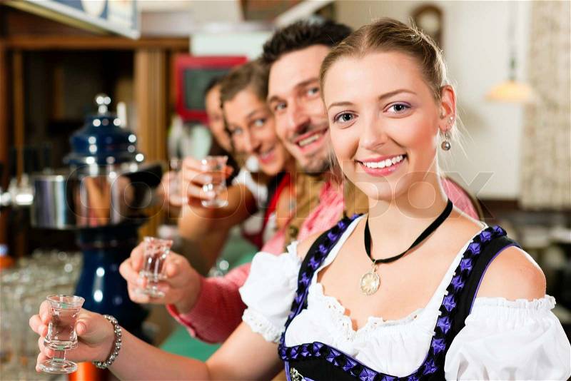 People in Bavarian Tracht drinking hard liquor in a pub and have fun, stock photo