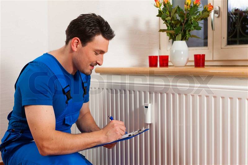 Technician reading the heat meter to check consumption, stock photo