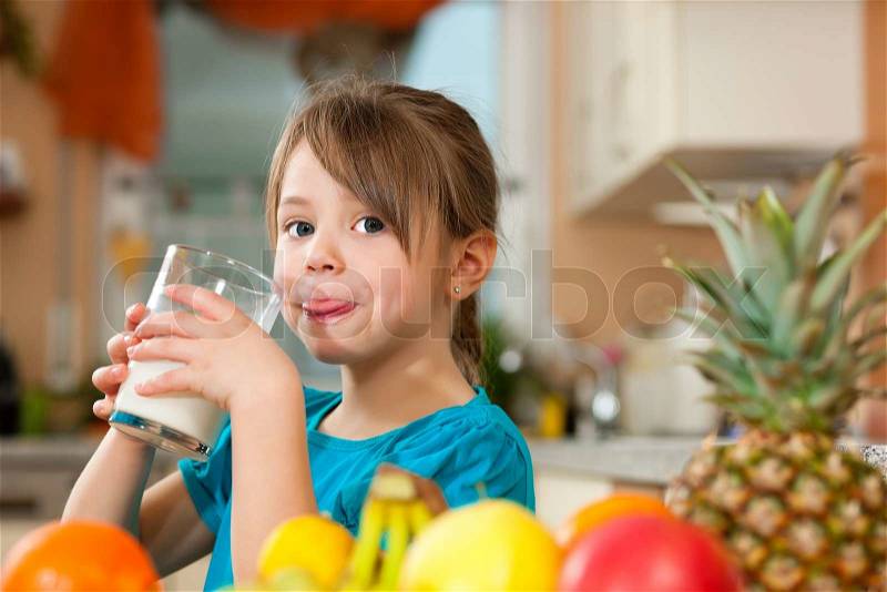 Healthy eating - Child drinking milk, lots of fresh fruit on the table in front, stock photo