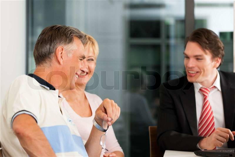 Mature couple with young financial consultant - they are planning their retirement, stock photo