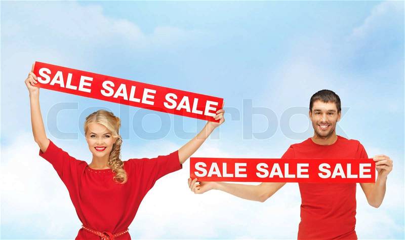Shopping, sale and christmas concept - smiling woman and man with red sale signs, stock photo