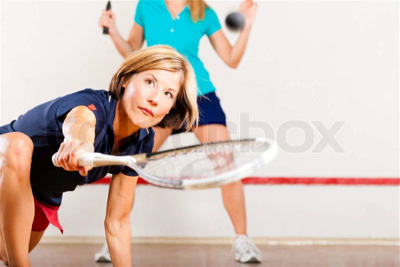 Two women playing squash as racket sport in gym, it might be a competition, stock photo