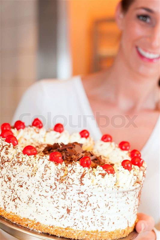 Female baker or pastry chef with torte in bakery, stock photo