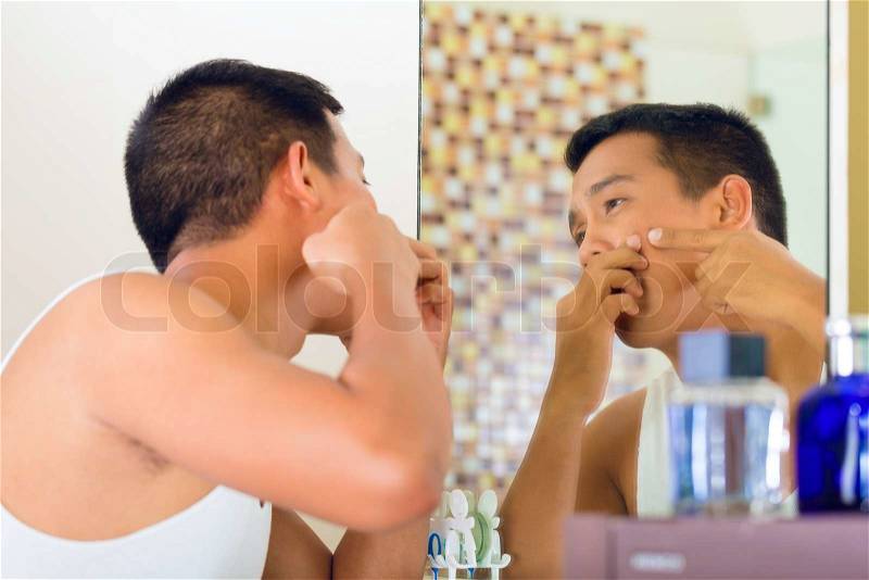 Asian man discovering a pimple in face, stock photo
