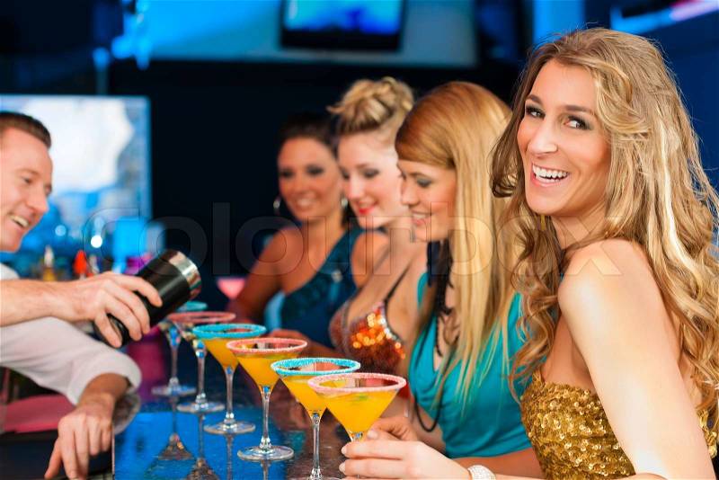 Young people in club or bar drinking cocktails and having fun; the barkeeper is mixing drinks, stock photo