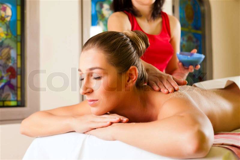 Woman receiving a massage in wellness spa by a masseuse, stock photo