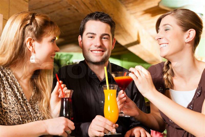 Young happy people drinking cocktails in bar or restaurant; presumably it is a little party, stock photo