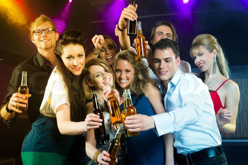 Young people in club or bar drinking beer out of a beer bottle and have fun, stock photo
