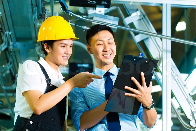 Worker or production manager and owner, ceo or controller, look on a Clipboard in a factory, stock photo