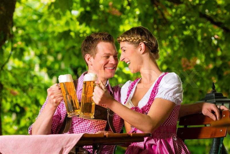 Happy Couple sitting in Beer garden in summer and enjoy a glass of beer and the sun, stock photo