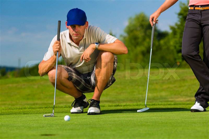 Young golf player on course putting, he aiming for his put shot, stock photo