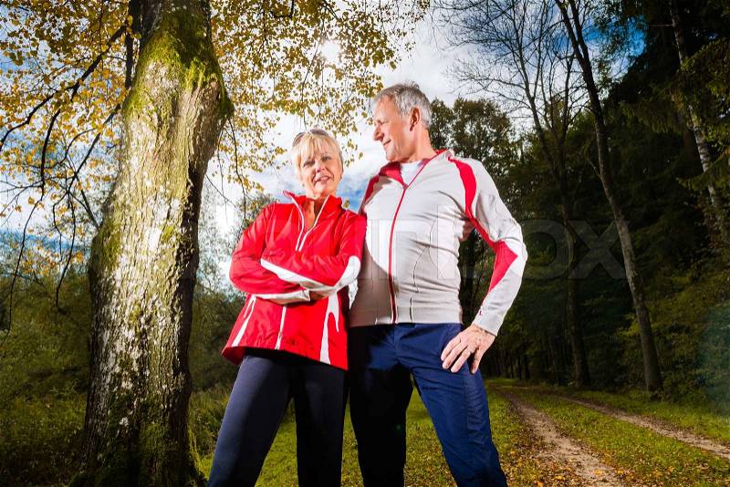 Senior Couple doing sport outdoor and posing on a forest road in the autumn, stock photo