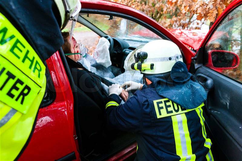 Accident - Fire brigade rescues accident Victim of a car, firefighter gives first aid, stock photo