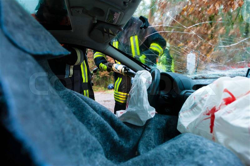 Accident - victim in a crashed vehicle, she receives medical first aid from firefighters, stock photo
