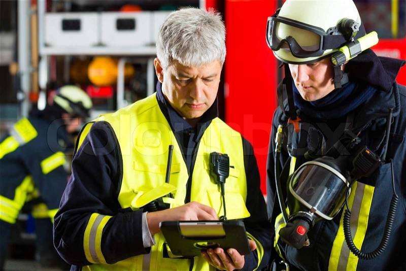 Fire brigade - Squad leader gives instructions, he used the Tablet Computer to plan the deployment, stock photo