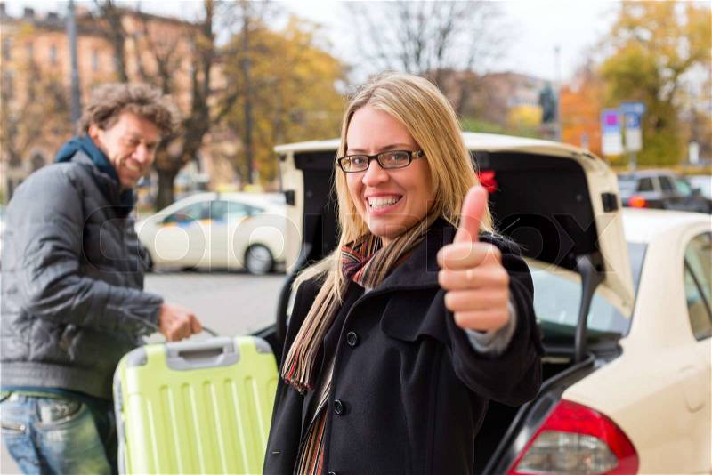 Young woman standing in front of taxi, she has reached her destination, the taxi driver will help with the luggage, stock photo