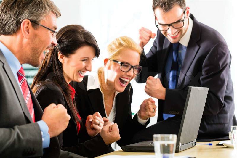 Business - Four professionals in office in business attire looking at laptop screen working together, they rejoice, stock photo