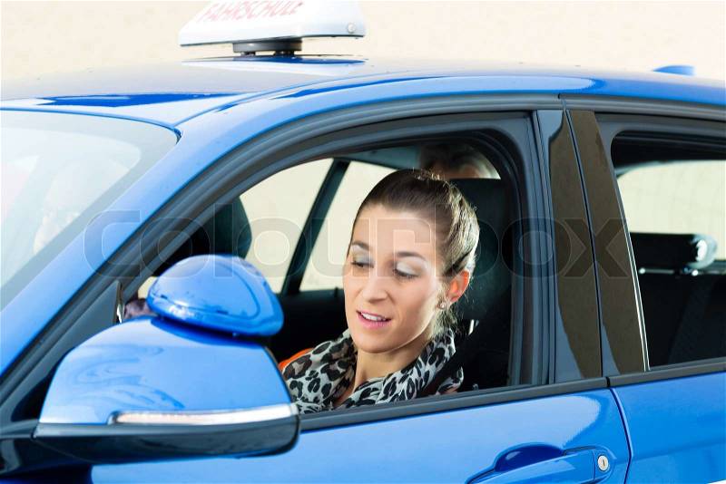 Driving School - Young woman steer a car, maybe she has a driving test and the driving examiner sits on the back seats, stock photo