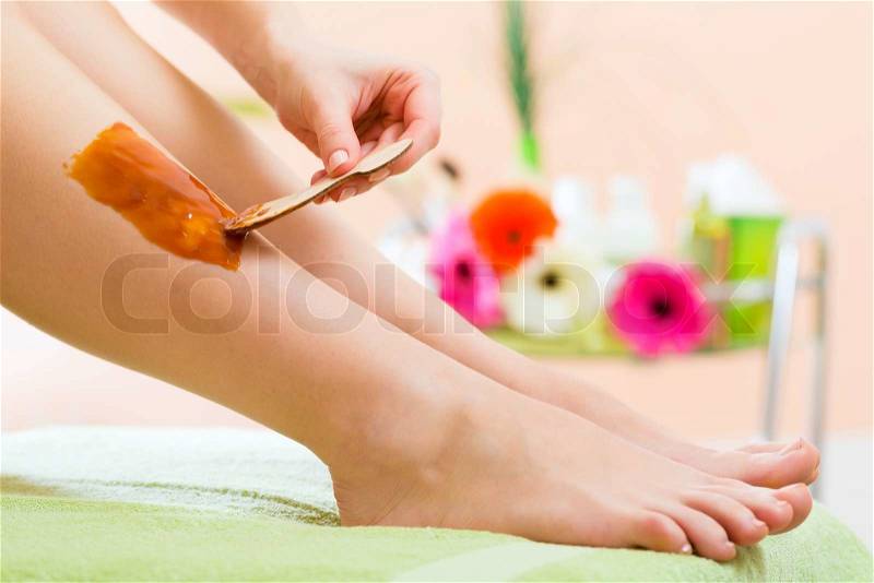 Young woman in Spa getting legs waxed for hair removal, stock photo